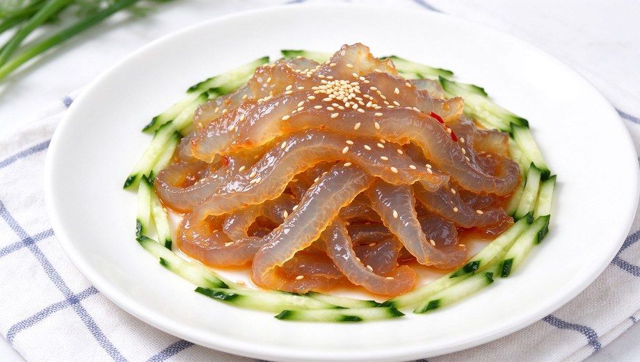 Chinese cold jellyfish salad with shredded cucumber, sesame seeds and chili on white plate, seafood appetizer