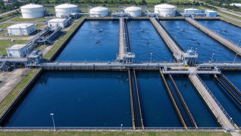 Aerial top-down view of large water treatment plant with clarification sedimentation tanks and storage tanks
