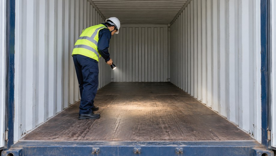 Inspector checking container dryness and condition before loading potassium alum cargo